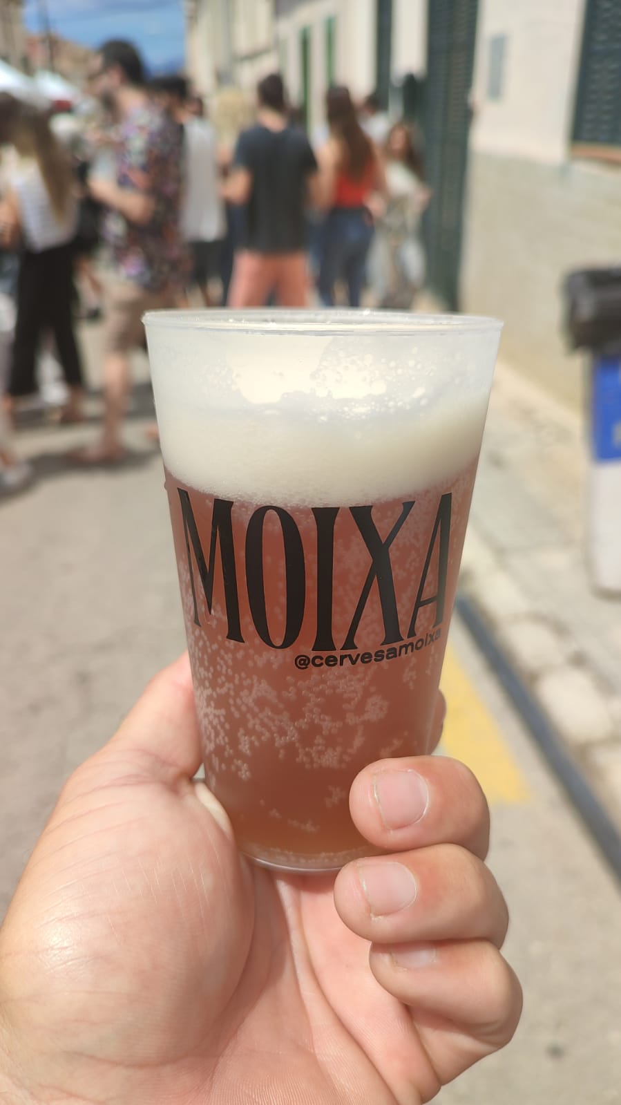 Tassó retornable ple de cervesa Moixa a un esdeveniment al carrer